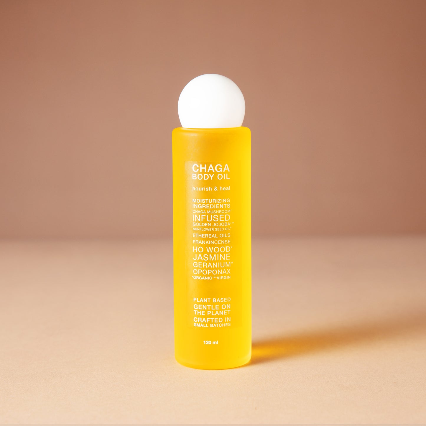 A bright yellow DEAR BOTANICS essential oil 120 ml bottle with a white spherical cap, standing on a beige surface against a warm beige background.