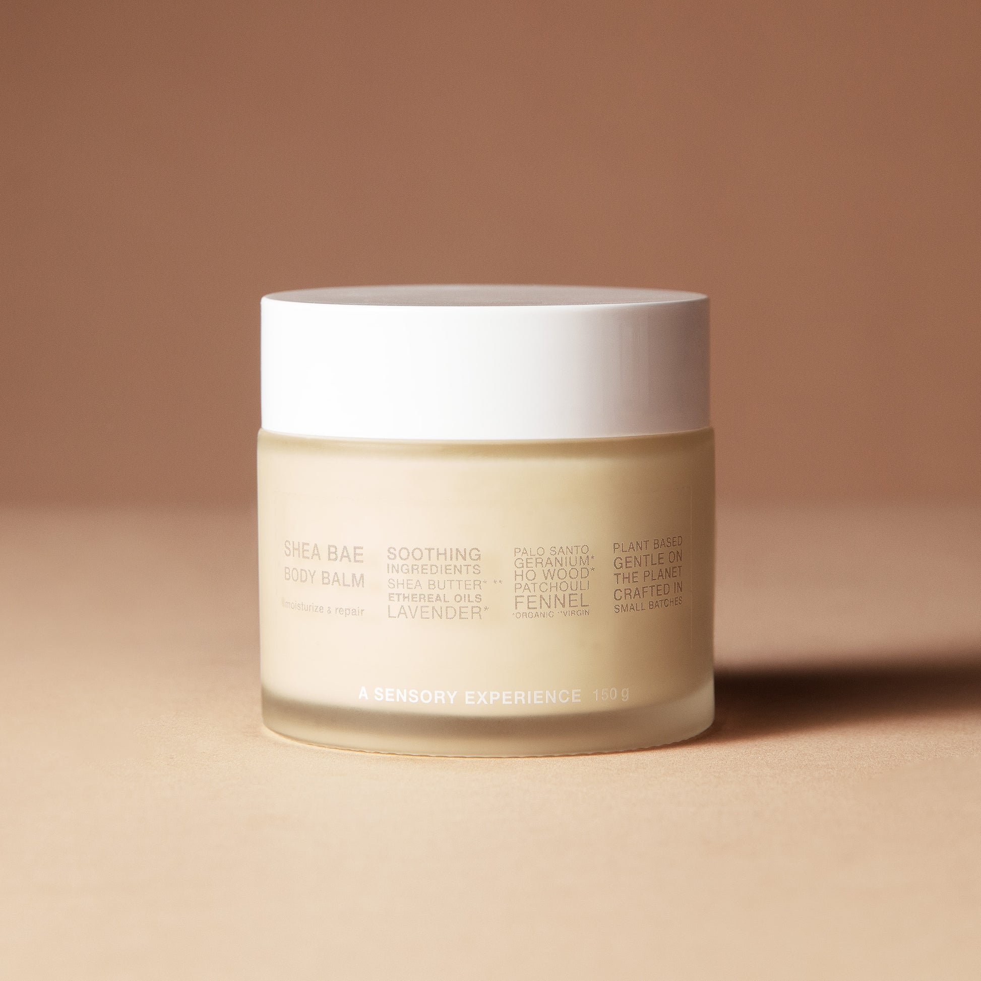 A 150 gram jar of DEAR BOTANICS shea butter cream, featuring a frosted beige glass container and a white lid, set against a warm beige background.