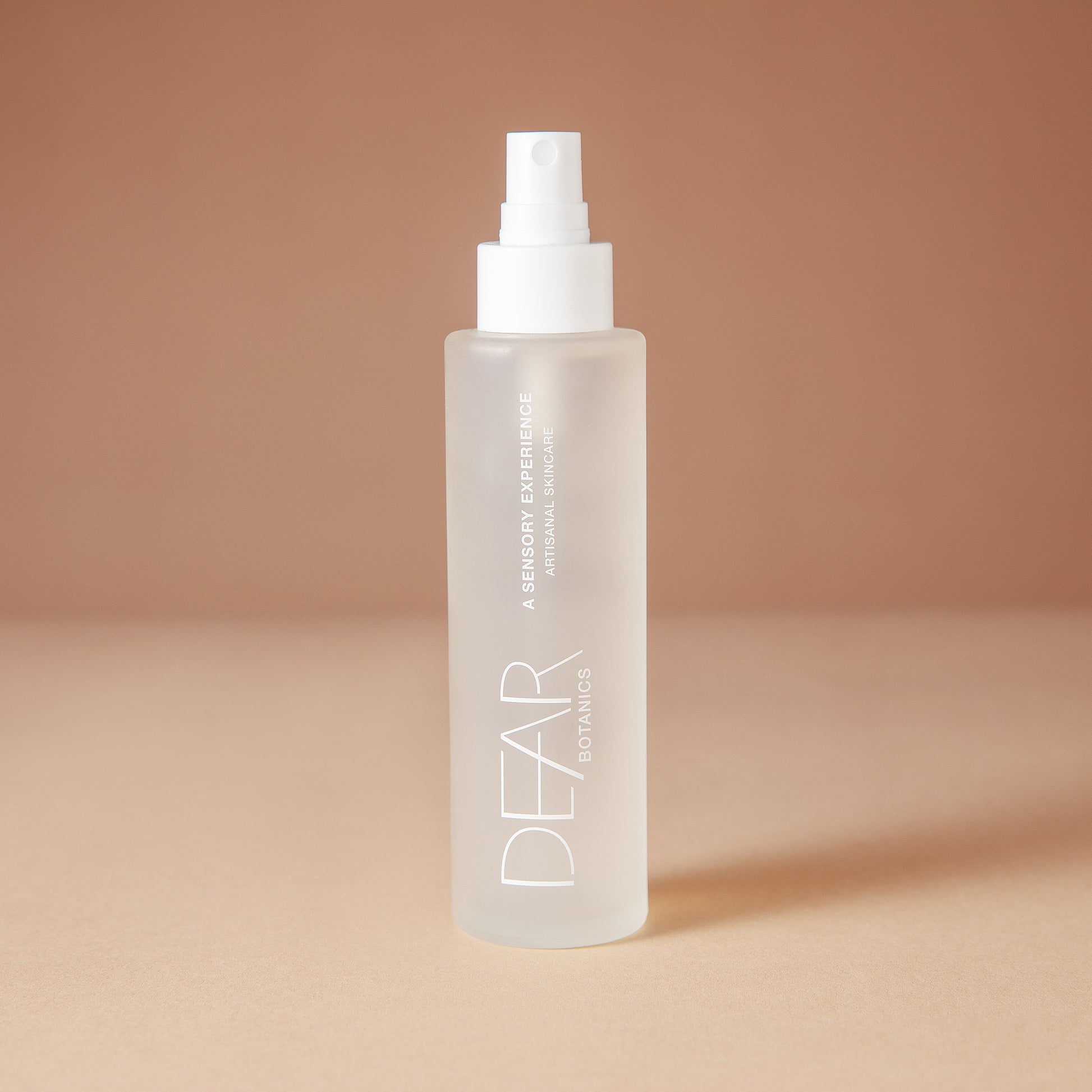 DEAR BOTANICS facial mist in a 120 ml frosted glass spray bottle with a white pump dispenser, set against a warm beige background.