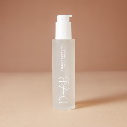 DEAR BOTANICS Face Wash in a 4 ounce frosted glass bottle with a white pump dispenser, set against a warm beige background.
